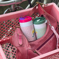 Dopper Travel Mug Large 400ml Berry Pink (roze) met versie Small Forest Green in roze tas in fietsmand