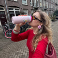 Dopper Travel Mug Large 400ml Berry Pink (roze) - vrouw met zwarte zonnebril op straat drinkt uit thermobeker