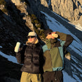Man en vrouw met bergwand op achtergrond drinken uit travel mug large forest green en earthy brown