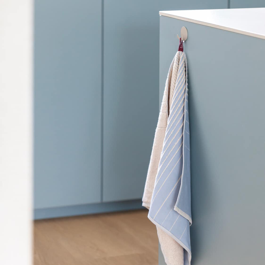 TweeDoek in lichtblauw, aan het lusje opgehangen bij een lichtblauw geverfd keukenblok