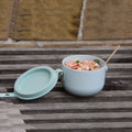 Uhmm Bowl  Lichtbaluw op houten buitentafel met salade gevuld.