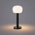 ELLE Decoration Vendome table lamp in matt black with the light on, against a grey background.