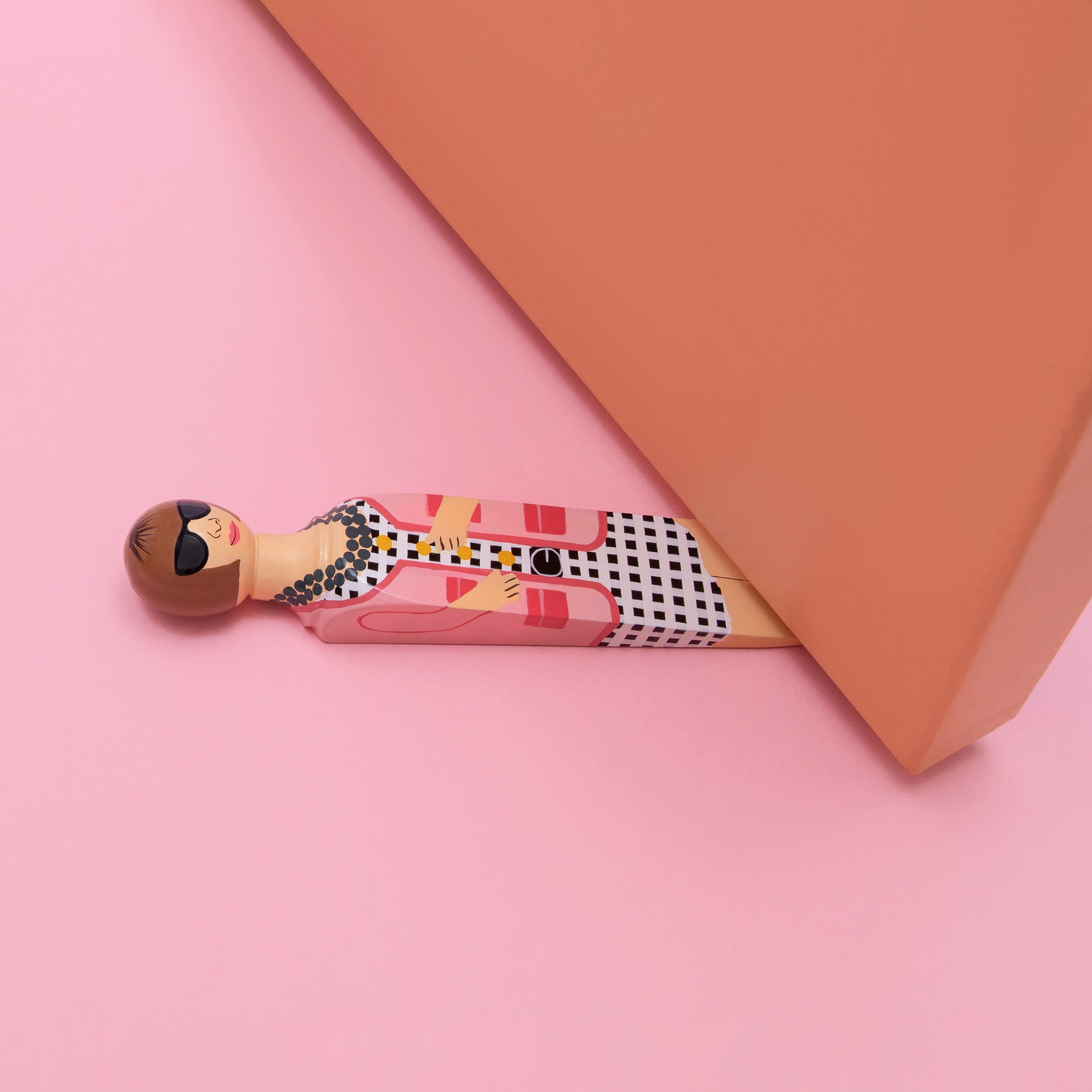 Wedgie Deurstopper Ana (Anna Wintour Look) bovenaanzicht liggend onder deur met roze ondergrond