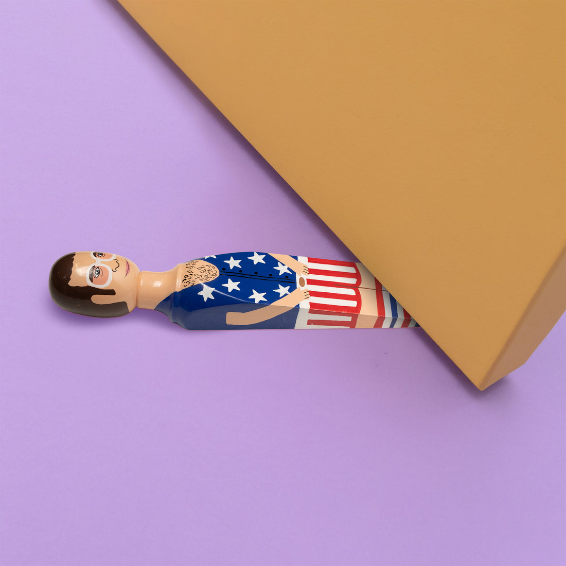 Wedgie Deurstopper Elty - Stars & Stripes (Elton John) - vooraanzicht met witte achtergrond en kleine ronde afbeelding onder deur rechtsboven