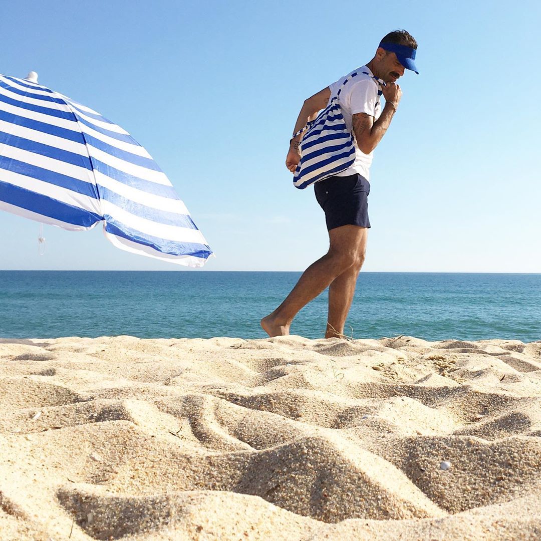 Man draagt Notabag Marine Stripes rugzak op het strand