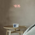 Braun Projectieklok en Wekker Digitaal BC15W-DCF│Wit│Radiogestuurd│op houten tafeltje met tijd op muur geprojecteerd