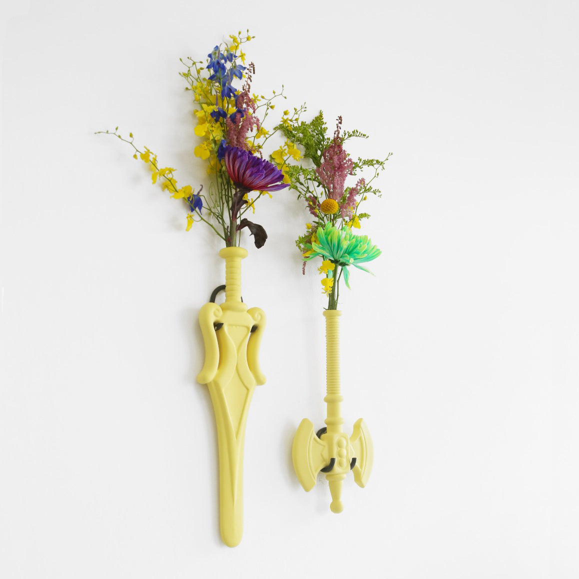 Flower Power Ax Vaas • Interieur • Een wandvaas in de vorm van een bijl of een zwaard. Handgemaakt van keramiek en ontworpen door Jasmin Djerzic. Hoewel dit symbolen lijken van geweld, staan ze voor de ontwerper gelijk aan speelsheid en creativiteit. Net als de speelgoedwapens voor kinderen.