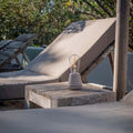 Humble One Outdoor Oplaadbare Tafellamp Linen│Buitenverlichting│art. UMTL00119│op houten tafeltje naast ligbed