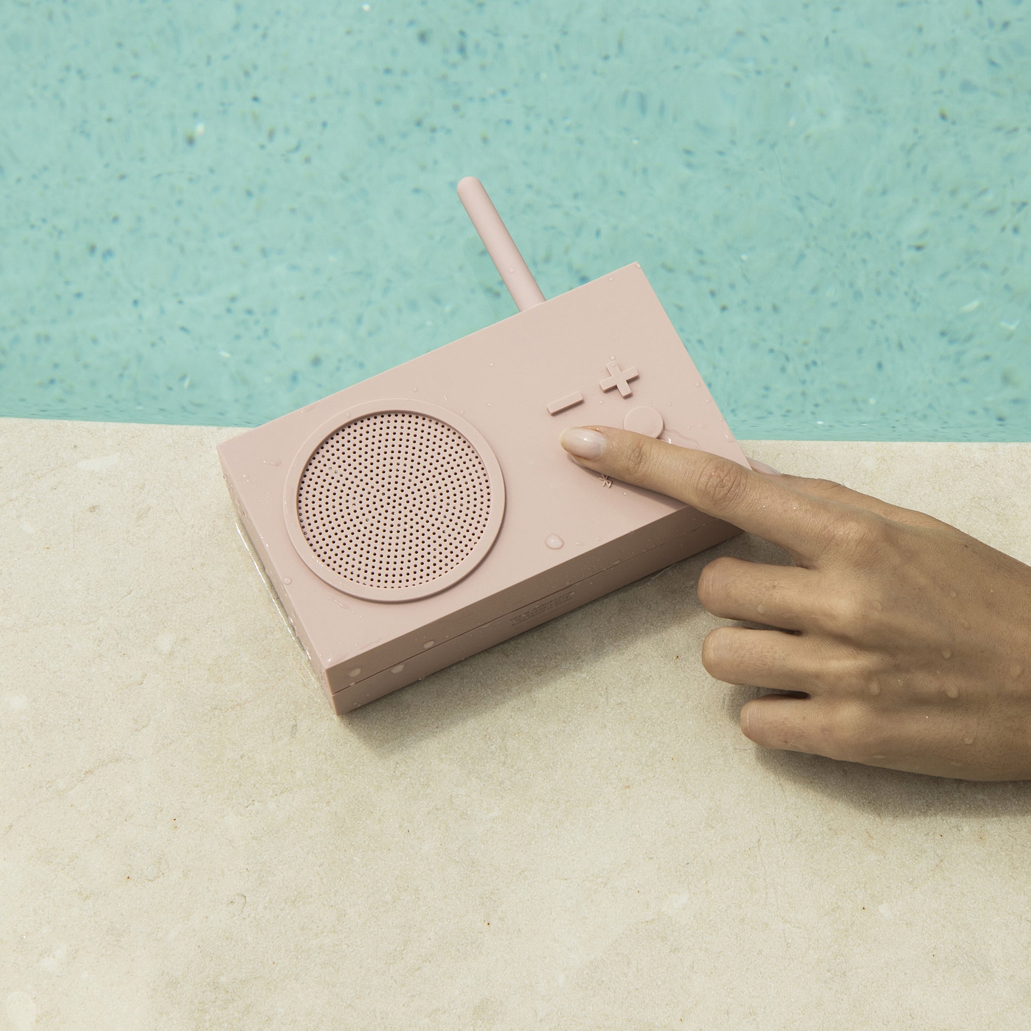 Lexon Tykho-3 FM Radio en Bluetooth-speaker│Roze│oplaadbaar│art.LA119P8│bij zwembad met hand op functie toets