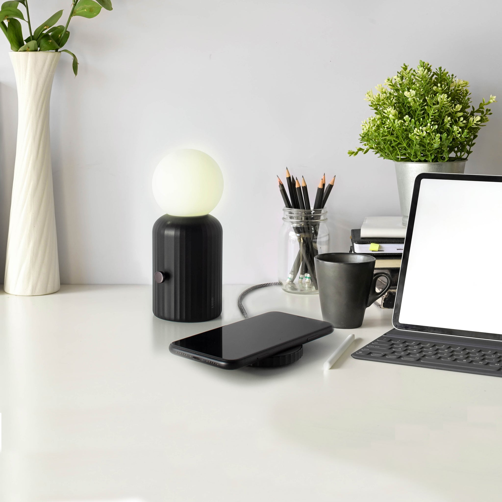 Skittle Oplaadbare Lamp Zwart│Lund London│Draadloos│lifestyle foto met laptop en telefoon op oplader