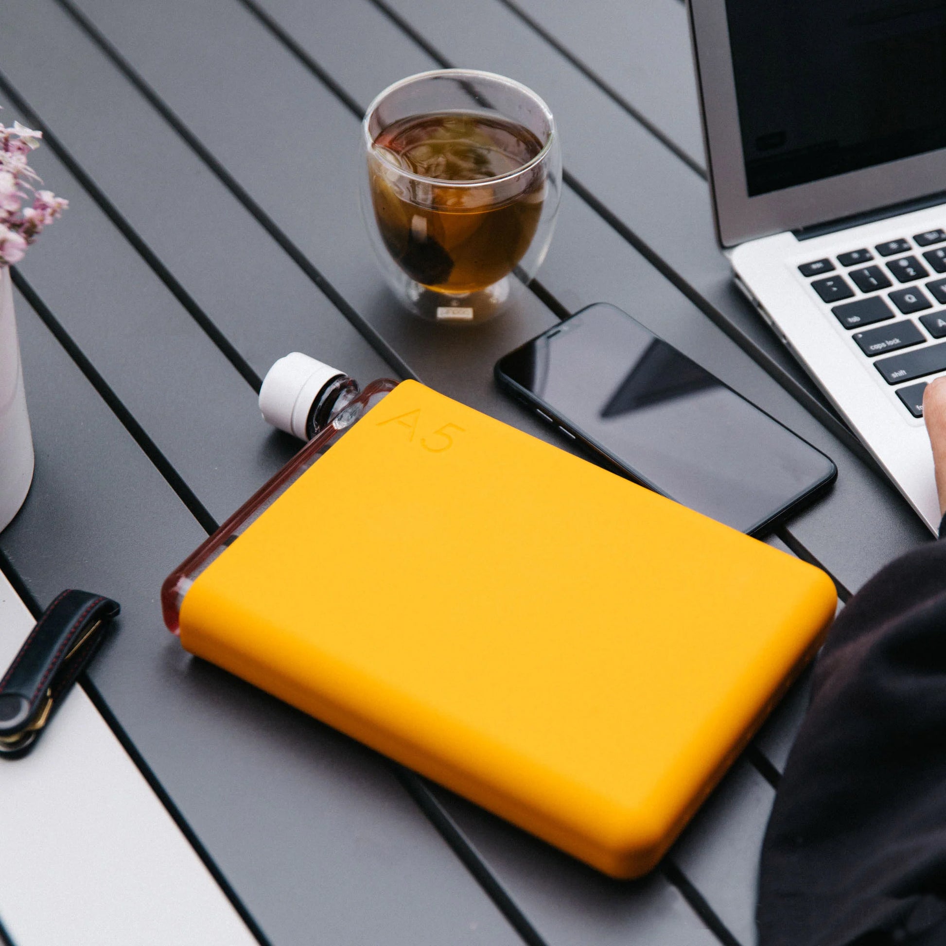 Memobottle Silicone Sleeve A5 Mandarin│Drinkfles│foto op buitentafel met laptop en telefoon