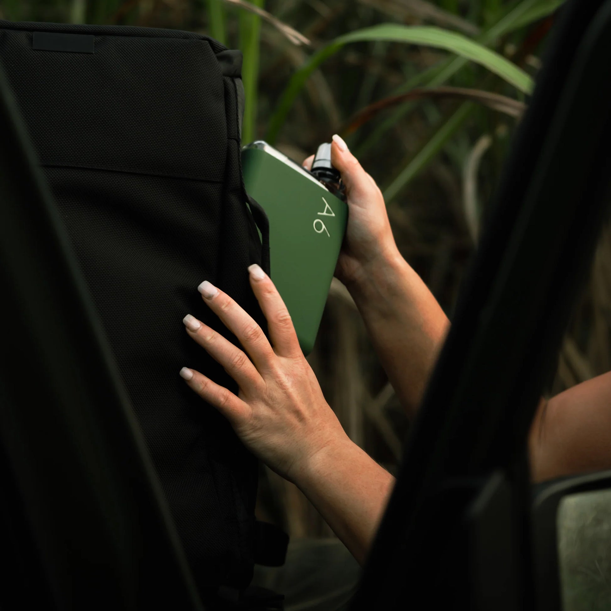 Memobottle Silicone Sleeve A6│Moss Green│foto met rugzak en struiken op achtergrond