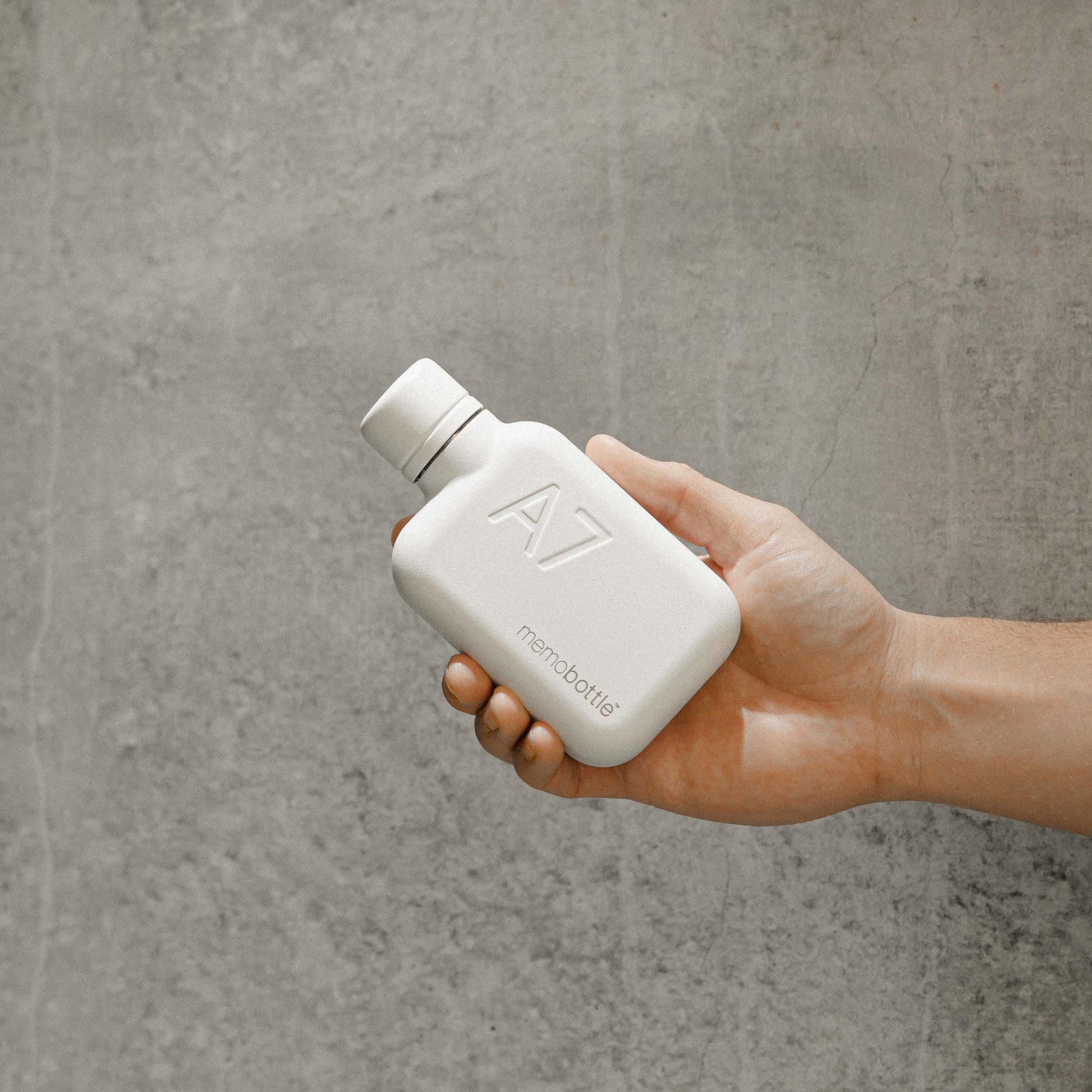 Memobottle Stainless Steel A7 Wit│drinkfles│foto in hand met betonnen achtergrond