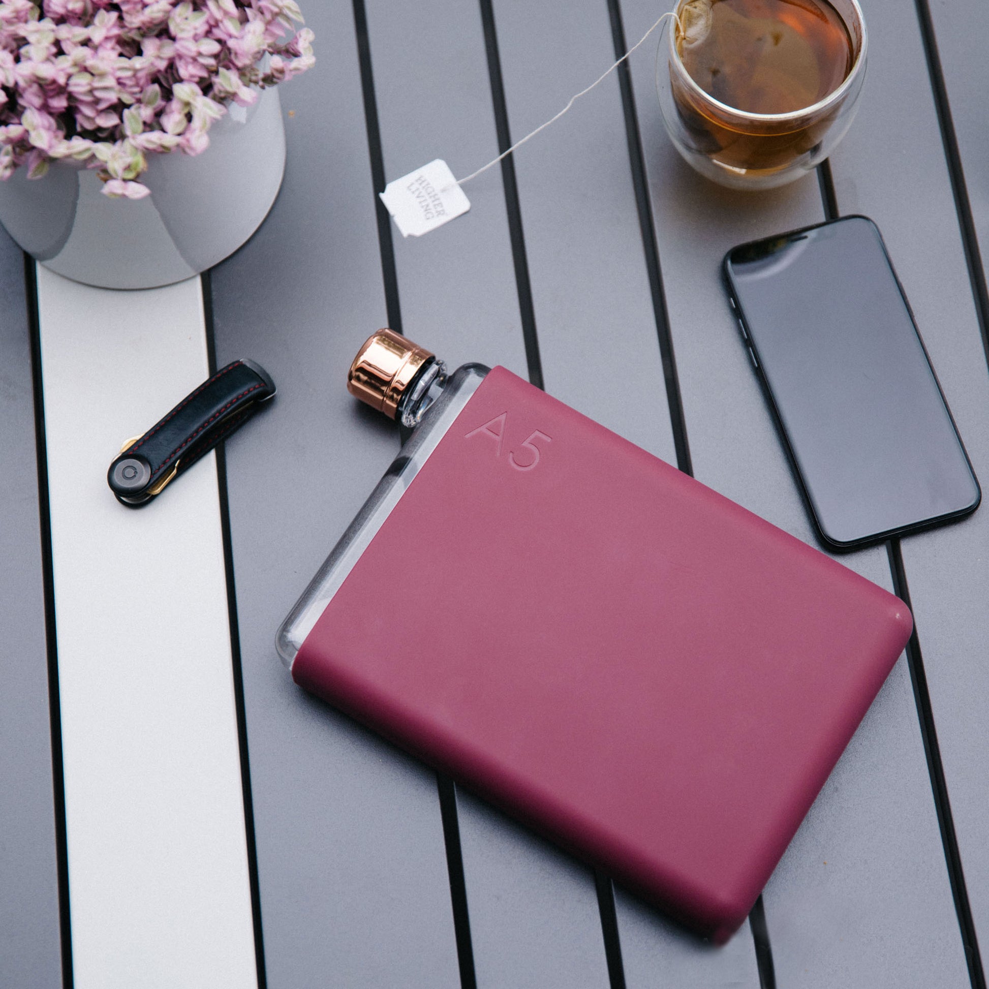 Memobottle Silicone Sleeve A5 wild Plum│Drinkfles│lifestyle foto op buitentafel met telefoon en orbitkey
