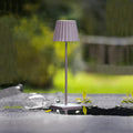 Sompex Troll 2.0 Roze│Oplaadbare tafellamp│Buitenverlichting│art. 78177│op buitentafel met regendruppes en leeg wijnglas