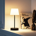 Oscar Oplaadbare Tafellamp Pure│Remember│Buitenverlichting│art. LT 01│in kast naast houten beeld en kunstboeken