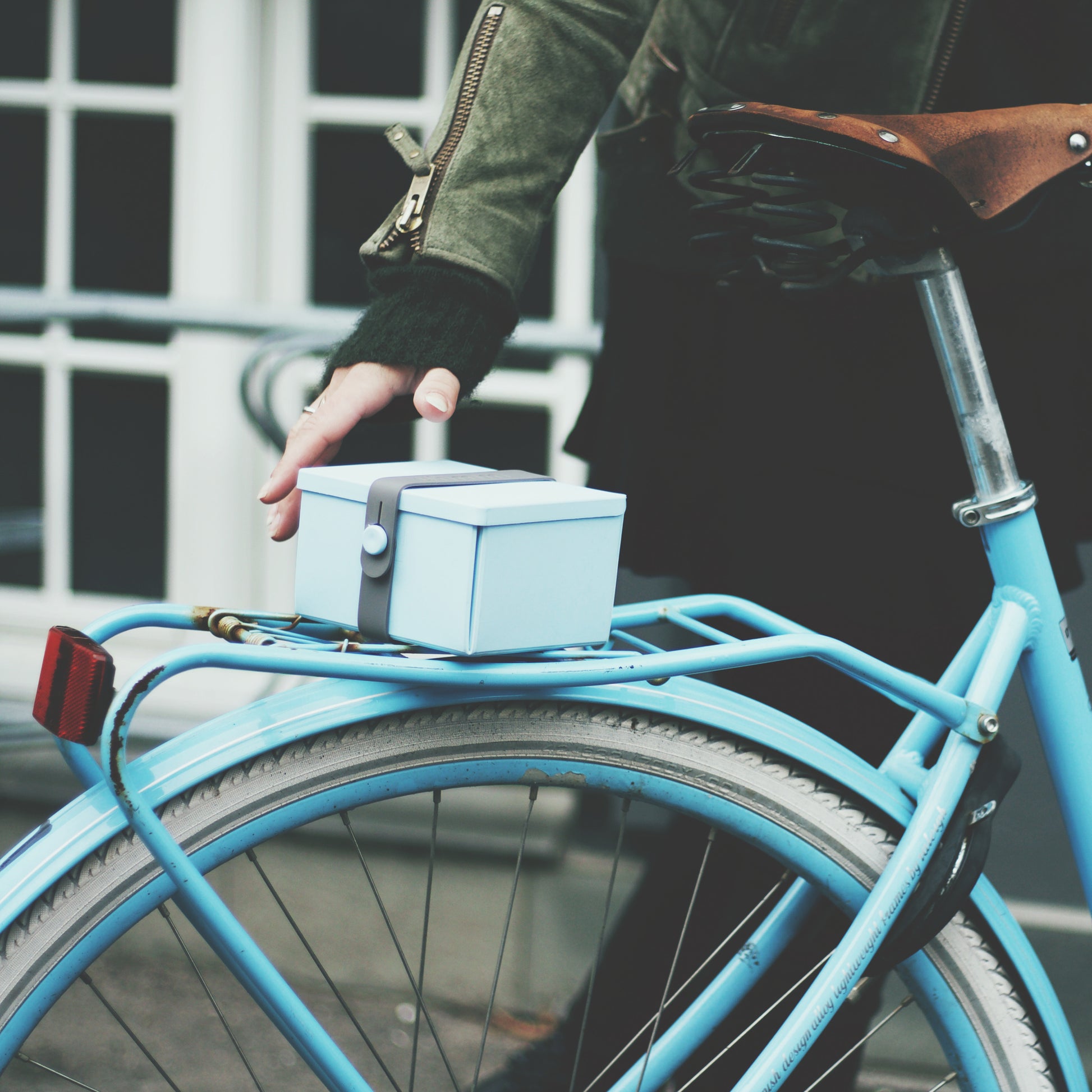 Uhmm 02 Opvouwbare Lunchbox Moring Mist│art. 981275│vrouw plaatst broodtrommel op blauwe fiets