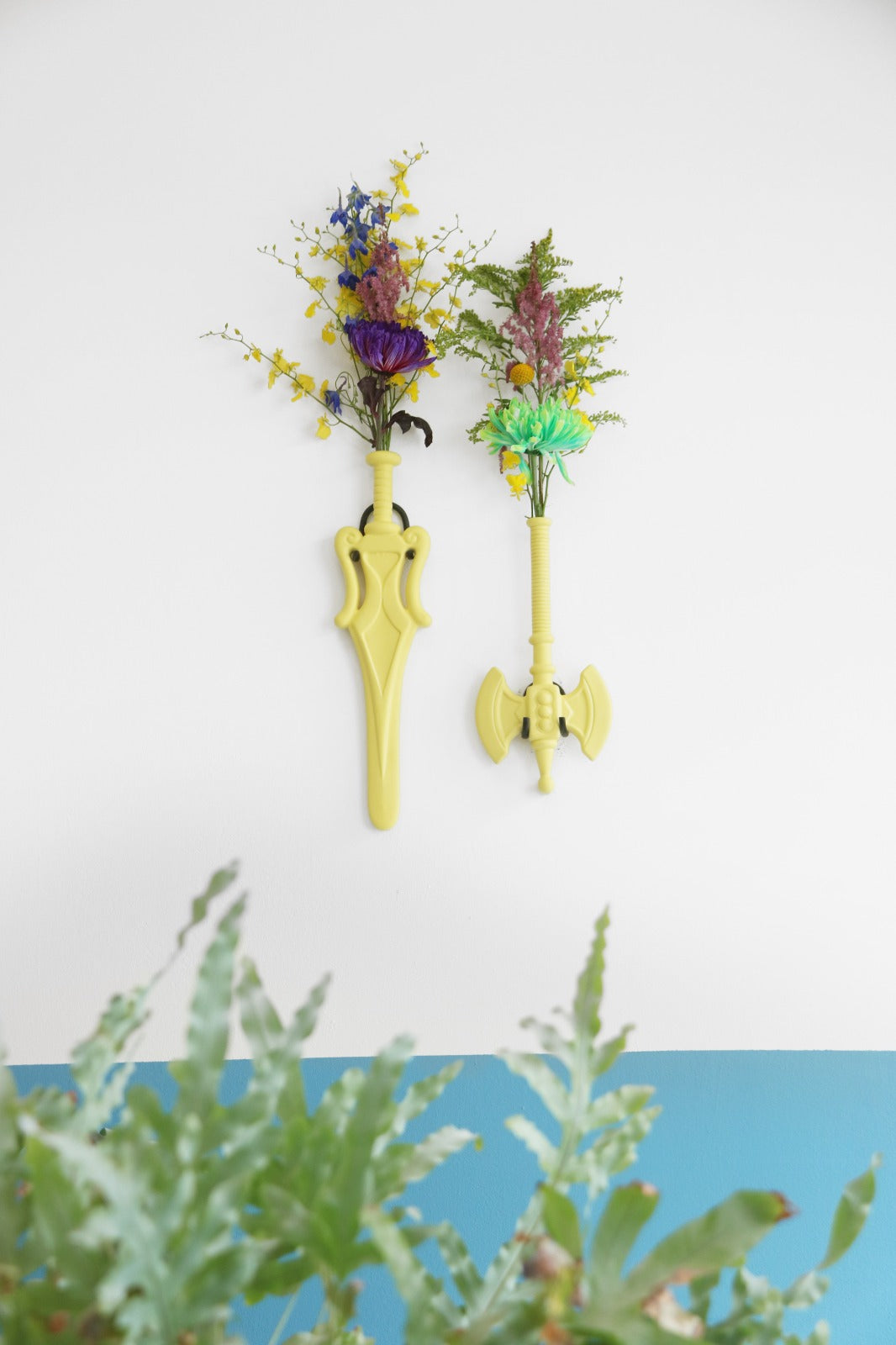 Flower Power Ax Vaas • Interieur • Een wandvaas in de vorm van een bijl of een zwaard. Handgemaakt van keramiek en ontworpen door Jasmin Djerzic. Hoewel dit symbolen lijken van geweld, staan ze voor de ontwerper gelijk aan speelsheid en creativiteit. Net als de speelgoedwapens voor kinderen.